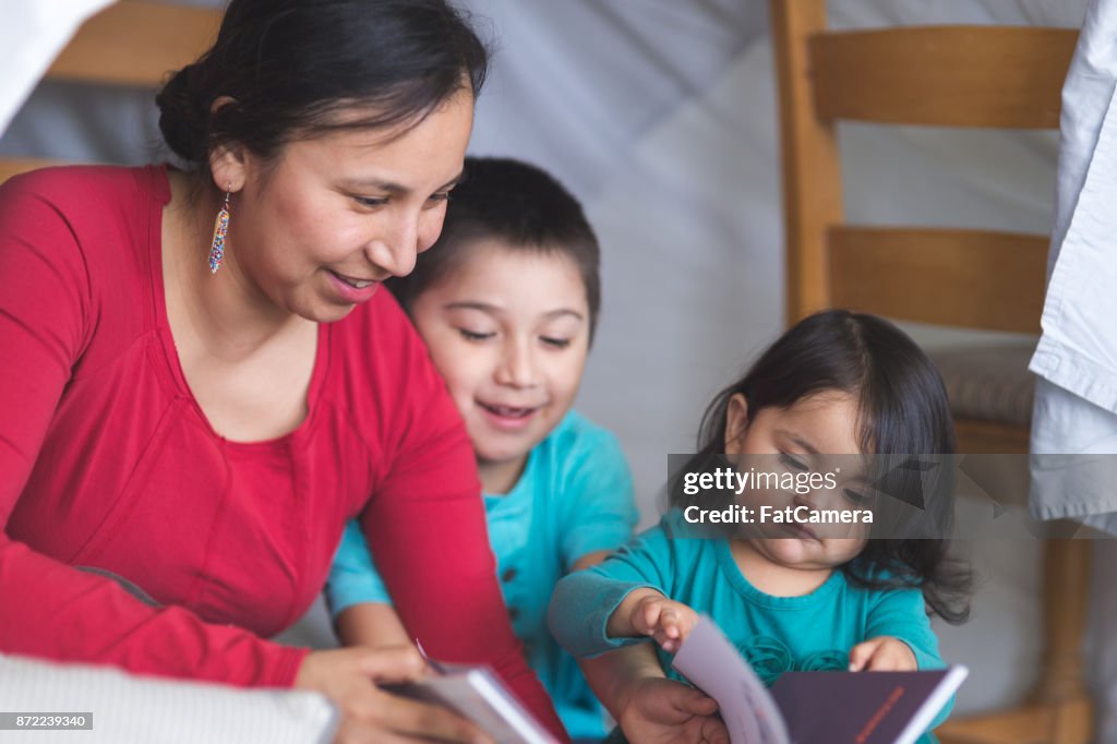 Native American mom reads with her son under makeshift fort in living room