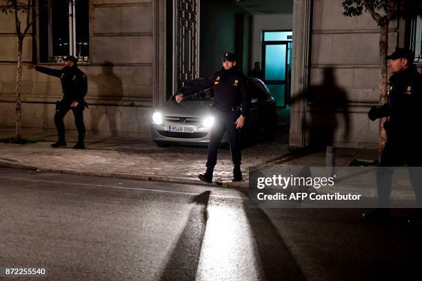 Spanish police officers stand guard as a police vehicle carrying the former speaker of Catalonia's dissolved regional parliament Carme Forcadell...