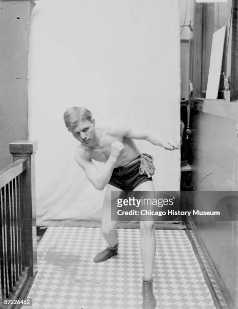 Full-length portrait of Oscar 'Battling' Nelson, boxer and lightweight champion, standing in boxing stance bending forward and right, left arm...