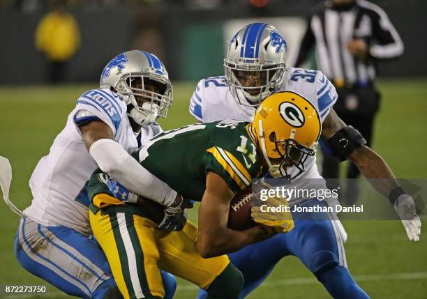 Trevor Davis of the Green Bay Packers is tackled by Nevin Lawson and Tavon Wilson of the Detroit Lions at Lambeau Field on September 28, 2017 in...