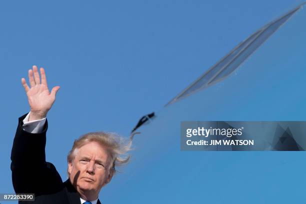 President Donald Trump waves as he boards Air Force One before flying to Vietnam to attend the annual Asia Pacific Economic Cooperation forum, at...