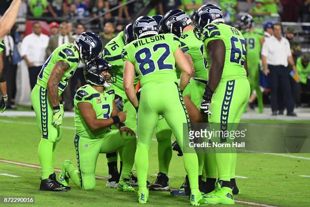 Quarterback Russell Wilson of the Seattle Seahawks talks to his team in a huddle in the first half of the NFL game against the Arizona Cardinals at...