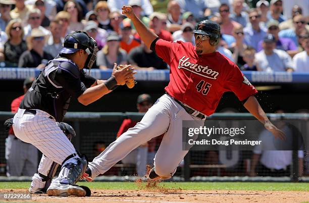 Carlos Lee of the Houston Astros slides into home and is tagged out by catcher Yorvit Torrealba of the Colorado Rockies as Lee tried to score on a...