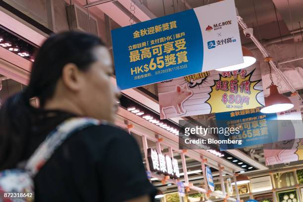 Shopper walks past advertisement banners for for Ant Financial Services Group's Alipay, an affiliate of Alibaba Group Holding Ltd., left and second...