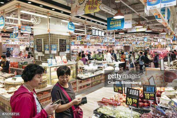 Shoppers walk past advertisements for Ant Financial Services Group's Alipay, an affiliate of Alibaba Group Holding Ltd., hanging above stalls inside...