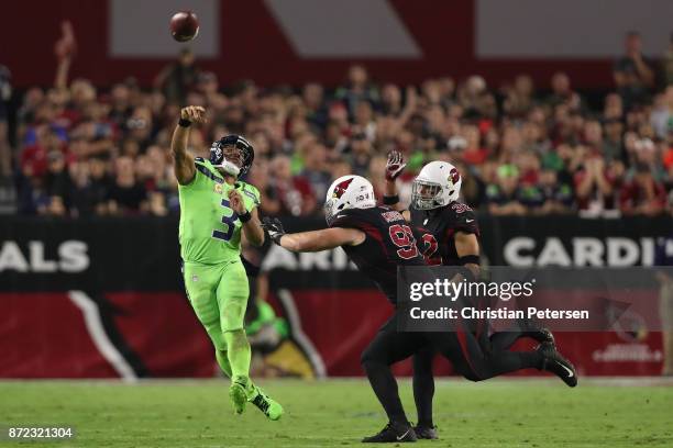 Quarterback Russell Wilson of the Seattle Seahawks scrambles to make a pass against defensive end Josh Mauro and free safety Tyrann Mathieu of the...