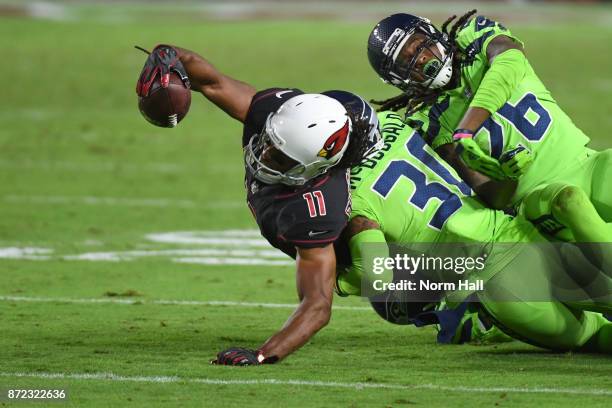 Wide receiver Larry Fitzgerald of the Arizona Cardinals completes a pass against defensive back Bradley McDougald and cornerback Shaquill Griffin of...