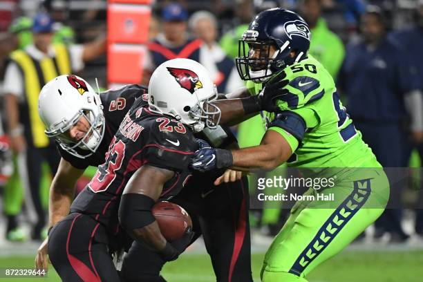 Outside linebacker K.J. Wright of the Seattle Seahawks tackles both quarterback Drew Stanton and running back Adrian Peterson of the Arizona...