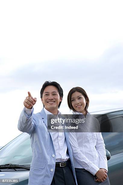 mature man pointing, leaning on car with woman - hawaii hemd stock-fotos und bilder