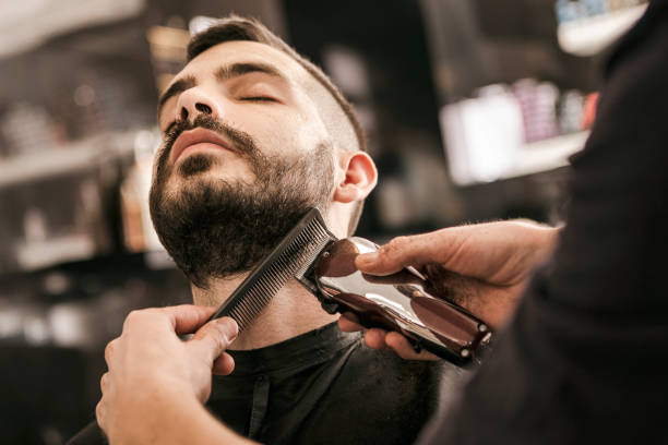 man getting his beard trimmed with electric razor - barber shop stock pictures, royalty-free photos & images