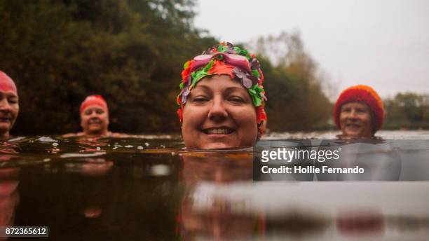 wild swimming women's group autumnal swim - swimming cap stock pictures, royalty-free photos & images