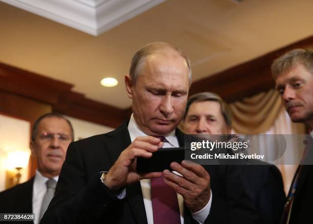 Russian President Vladimir Putin holds an iPhone as his spokesman Dmitry Peskov looks on prioir to a bilateral meeting with Philippines President...