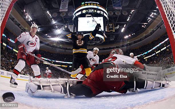 Milan Lucic of the Boston Bruins scores a goal in the third period to force overtime as Cam Ward and Rod Brind'Amour of the Carolina Hurricanes...