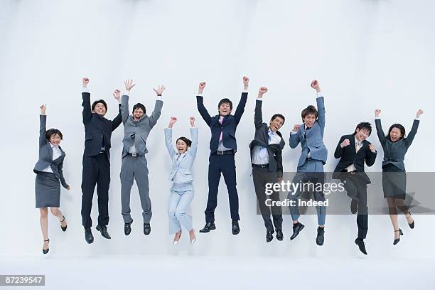 business people jumping and clenching fists - frau arme hoch ganzkörper stock-fotos und bilder