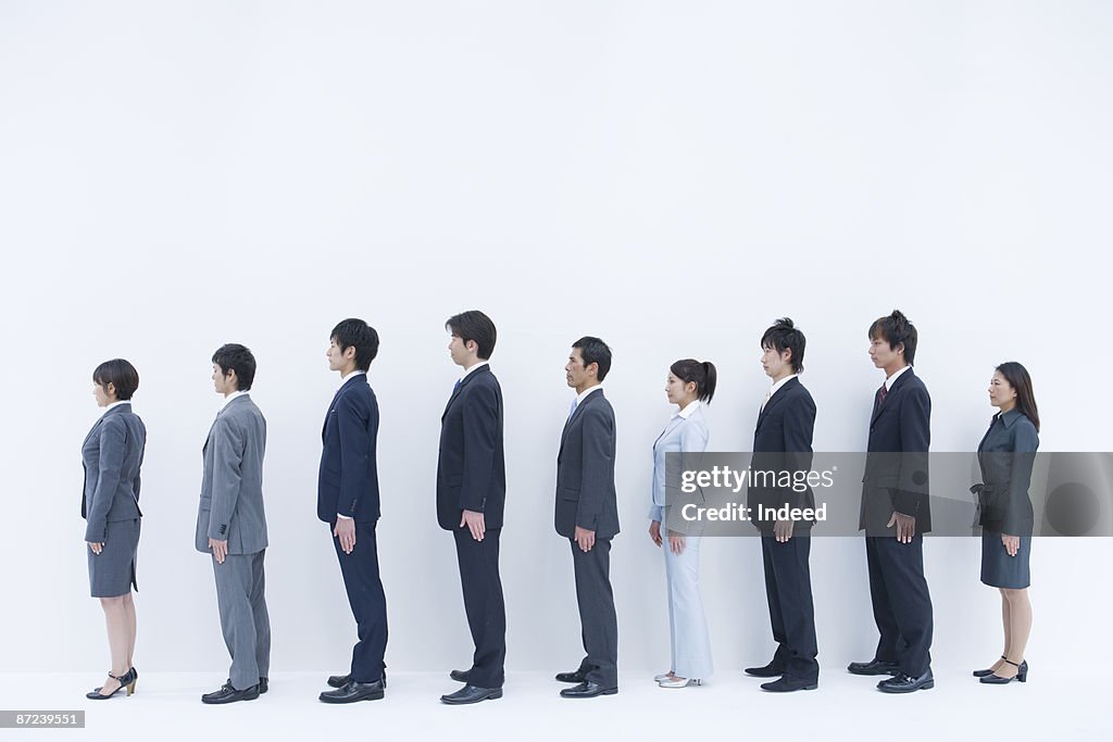 Business people standing in a row, side view