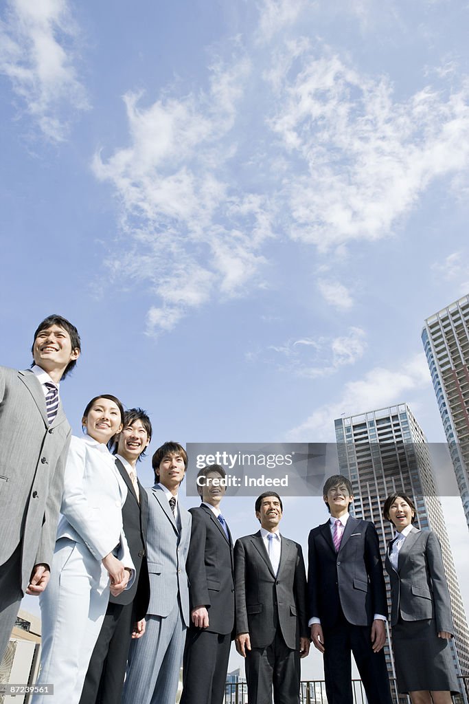 Business people standing in a row, smiling