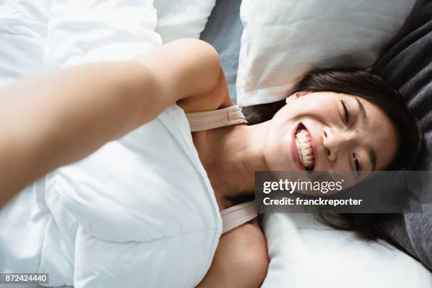 chinese woman taking a selfie on the bed - girl in her bed stock pictures, royalty-free photos & images