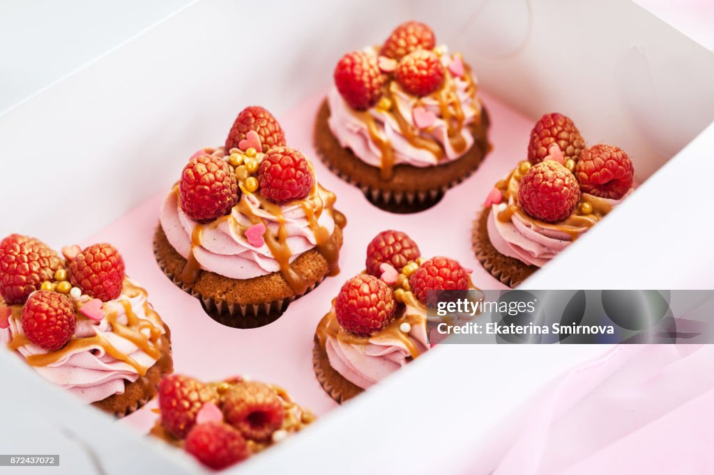 Delicious raspberry and caramel cupcakes in paper box