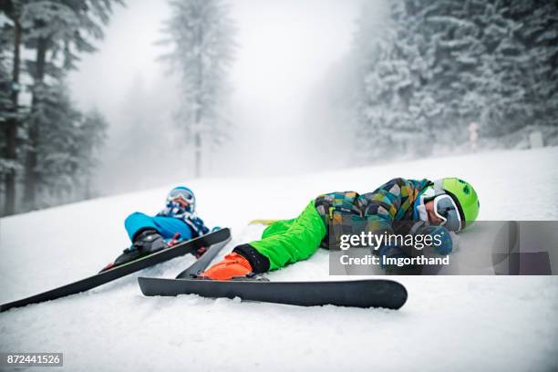 kleinen skifahrer nach einem sturz am hang liegen - zusammenprall stock-fotos und bilder