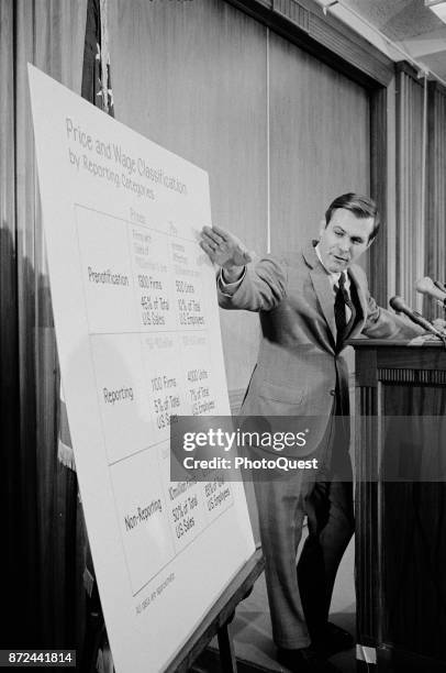 American politician and Director of the Cost of Living Council Donald Rumsfeld gestures towards a chart headed 'Price and Wage Classification by...