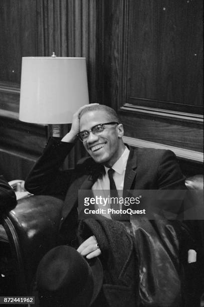 American Religious and Civil Rights leader Malcolm X laughs as he sits in an armchair before a press conference , Washington DC, March 26, 1964.