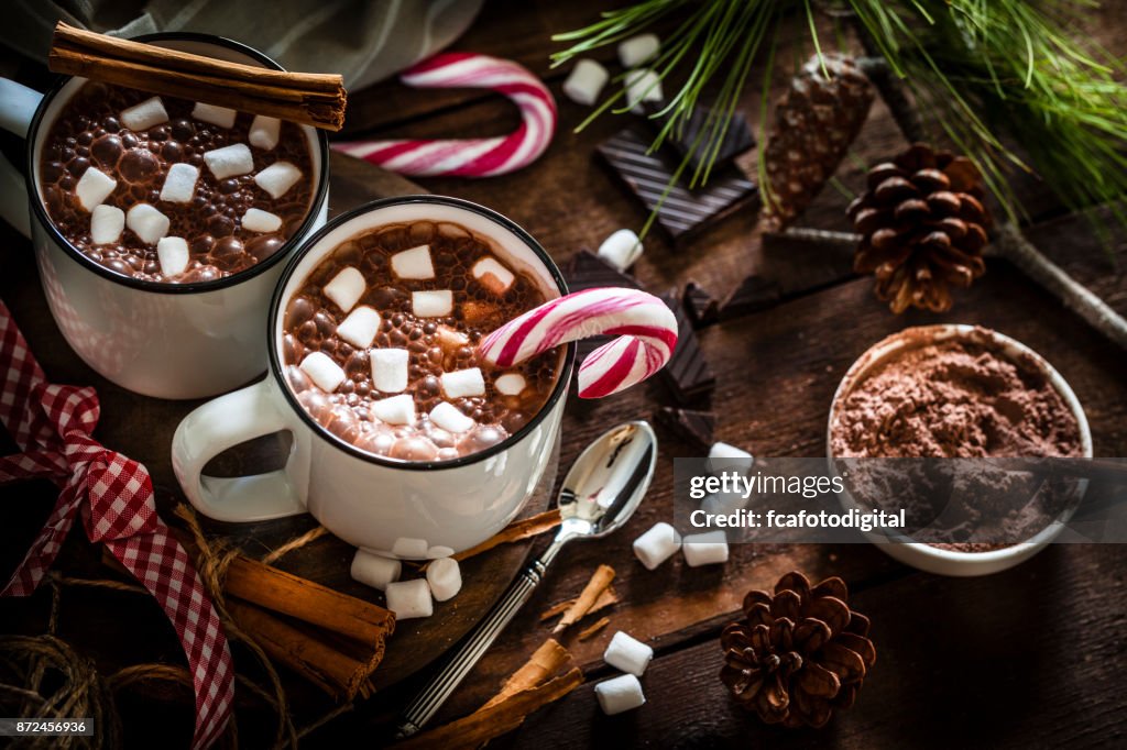 Dos tazas de chocolate caliente caseras con malvaviscos en la mesa de Navidad de madera rústica