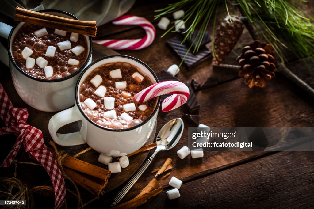 Dos tazas de chocolate caliente caseras con malvaviscos en la mesa de Navidad de madera rústica