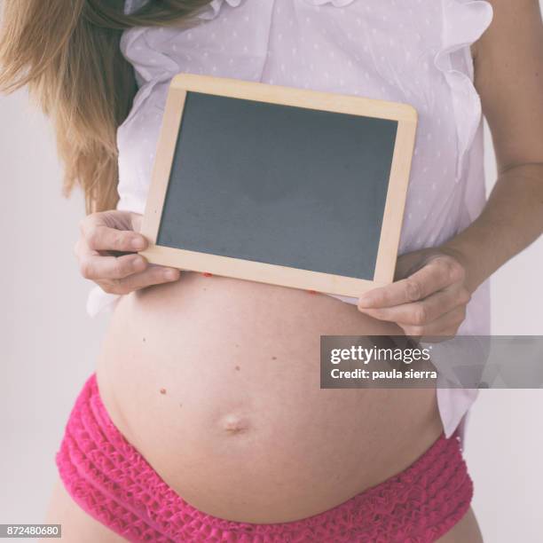 a pregnant woman is holding a blackboard - tanga stock-fotos und bilder