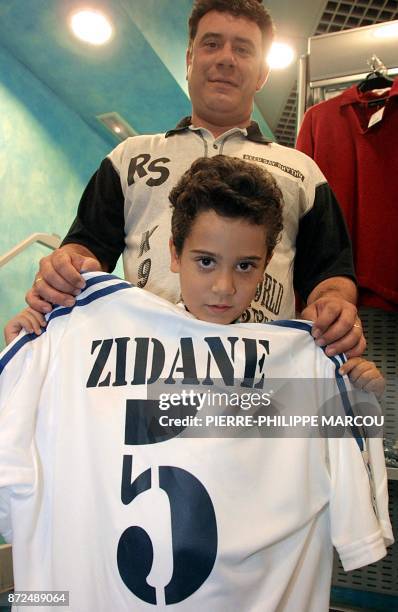 Man and his son 10 July 2001 hold a replica of a Real Madrid shirt wearing the name of French international Zinedine Zidane and his new number five,...