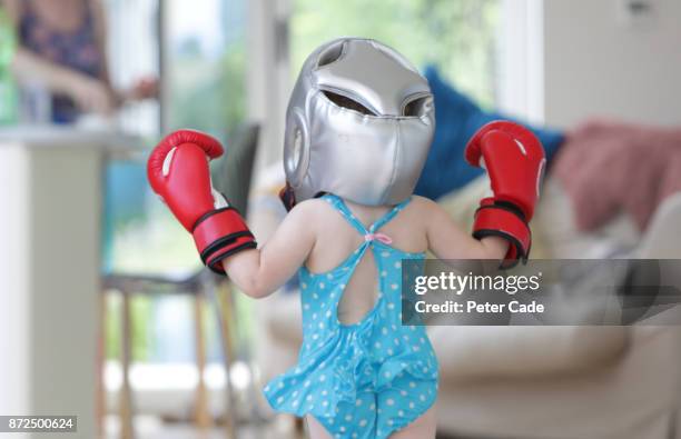 toddler girl running around house in swimming costume and boxing clothes - funny boxing stock-fotos und bilder