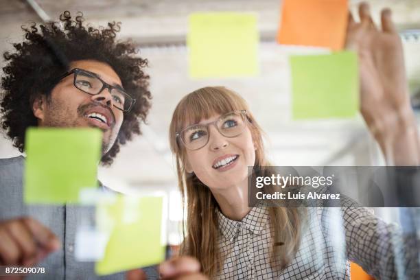 businesswoman with colleague discussing over adhesive notes - grünes hemd stock-fotos und bilder