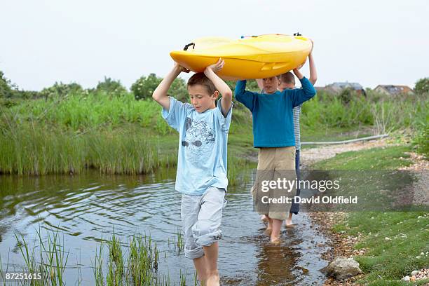 boy carrying canoe in wetlands - carrying canoe stock pictures, royalty-free photos & images