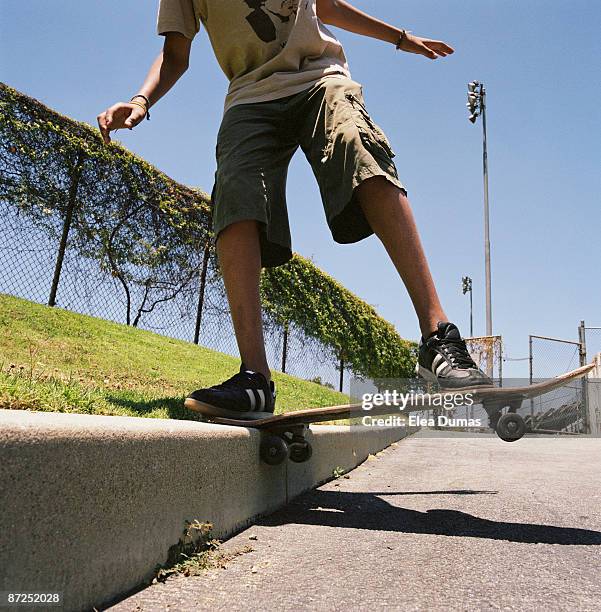 teenage boy balancing skateboard on sidewalk curb - kerb stock pictures, royalty-free photos & images