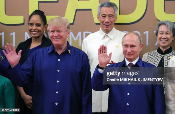 President Donald Trump and Russia's President Vladimir Putin wave as they pose for a group photo ahead of the Asia-Pacific Economic Cooperation...