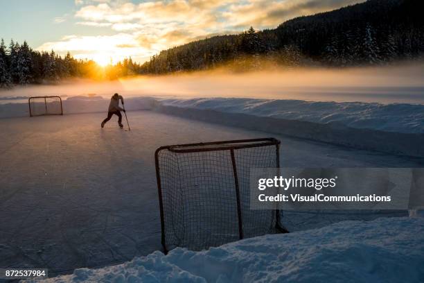 junger mann spielt hockey auf zugefrorenen see. - pond hockey stock-fotos und bilder