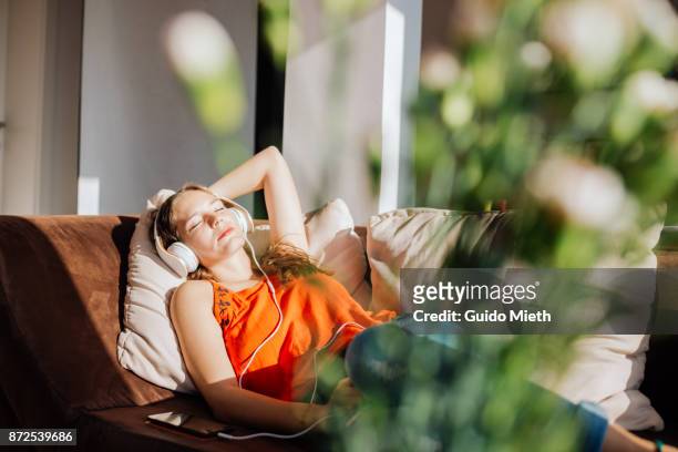 woman relaxing in sunlight. - listening stock-fotos und bilder