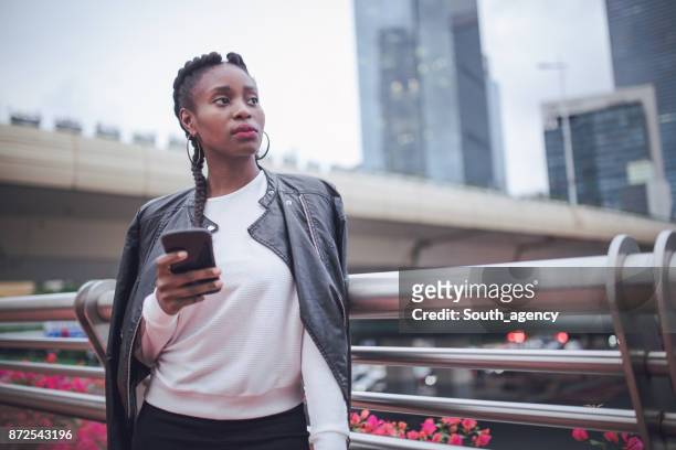 woman in biker jacket texting on the phone - biker jacket stock pictures, royalty-free photos & images