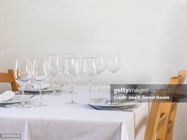 restaurant table prepared with white tablecloth, napkins, cutlery and wine glasses, with wooden chairs on a white background - la belle équipe restaurant ストックフォトと画像