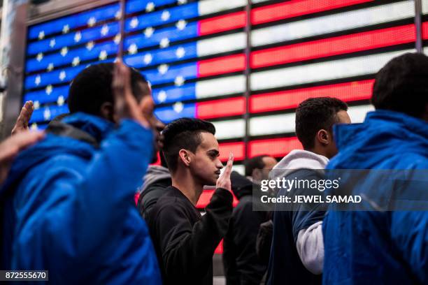 New recruits raise their hands as they take an oath outside the renovated Times Square Military Recruiting Station in New York on November 10, 2017.