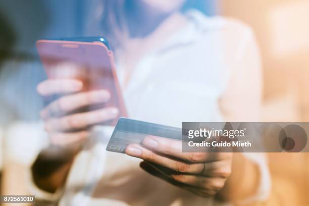 shopping online with smartphone and credit card on hand. - credit card stock-fotos und bilder