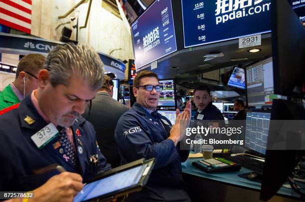 Traders work beneath monitors displaying PPDAI Group Inc. Signage on the floor of the New York Stock Exchange in New York, U.S., on Friday, Nov. 10,...