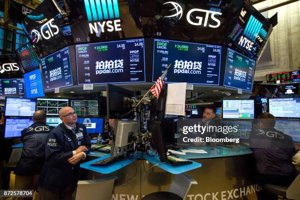 Traders work beneath monitors displaying PPDAI Group Inc. Signage on the floor of the New York Stock Exchange in New York, U.S., on Friday, Nov. 10,...