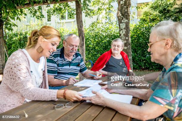 volunteer woman assisting seniors with coloring and drawing - volunteer aged care stock pictures, royalty-free photos & images