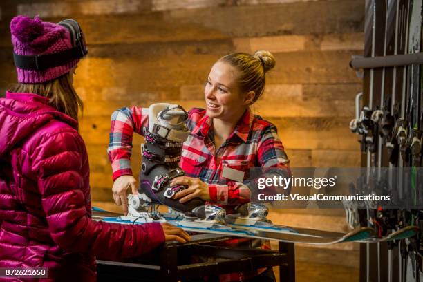 mujer asistente de ventas afinando esquís para el cliente. - traje de esquí fotografías e imágenes de stock