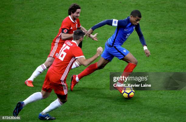 Kylian Mbappe of France in action with Joe Allen and Joe Ledley of Wales during the friendly match between France and Wales at Stade de France on...