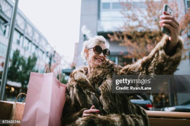 stijlvolle en eigenzinnige senior vrouw neemt selfie - black friday shoppers stockfoto's en -beelden