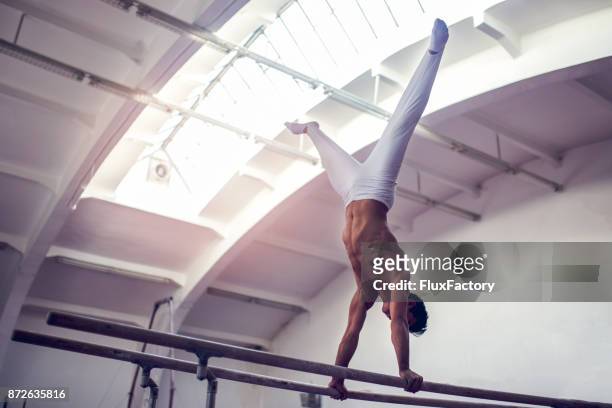 male gymnast practicing on parallel bars - artistic gymnastics stock pictures, royalty-free photos & images