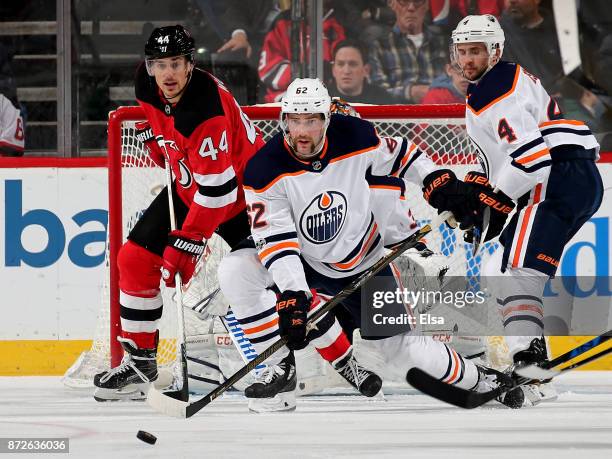 Miles Wood of the New Jersey Devils and Eric Gryba of the Edmonton Oilers fight for the puck on November 9, 2017 at Prudential Center in Newark, New...