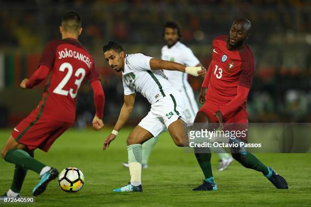 Joao Cancelo and Danilo Pereira of Portugal competes for the ball with Salem AlDawsari of Saudi Arabia during the International Friendly match...