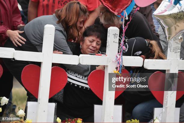 Lilly Navejan is comforted after breaking down while visiting a memorial where 26 crosses were placed to honor the 26 victims killed at the First...